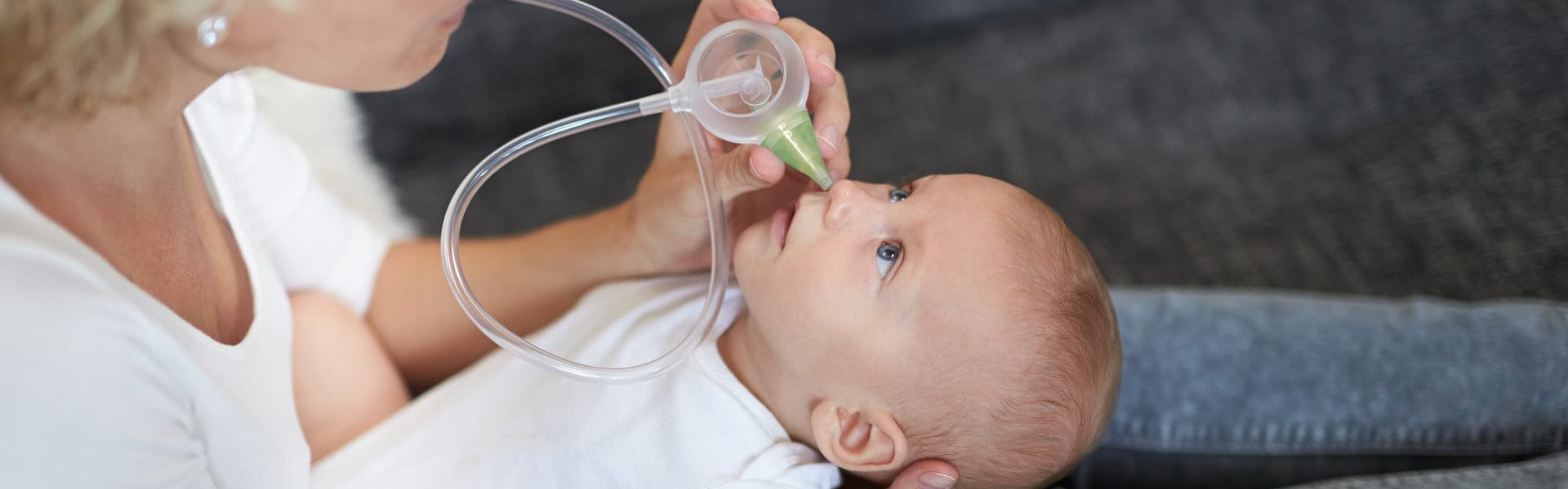 A woman clearing the baby's nose with the help of the Nosiboo Eco Manual Nasal Aspirator