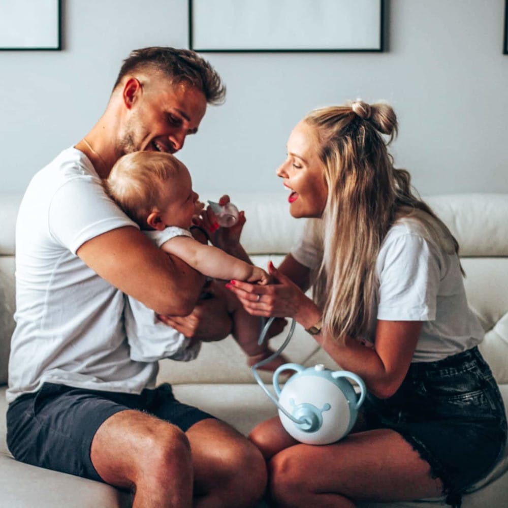A mom and dad together aspirating the nose of their baby with a Nosiboo Pro electric nasal aspirator