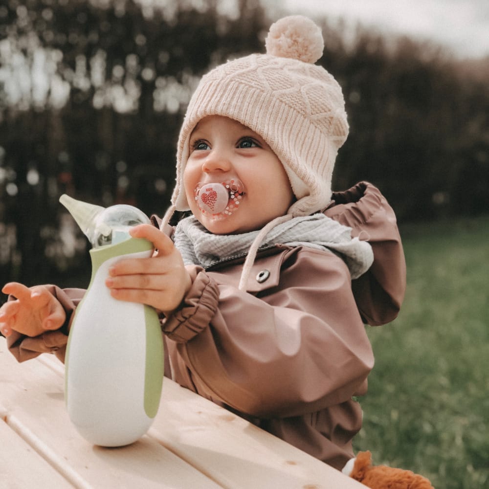 Little girl outside in warm clothes holding a Nosiboo Go portable electric nasal aspirator