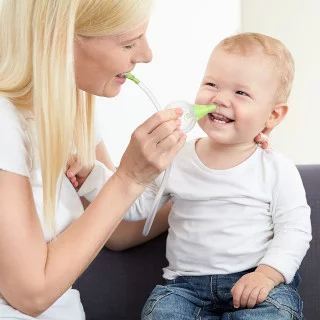 A woman clearing the nose of her smiling son with the help of the Nosiboo Eco Manual Nasal Aspirator