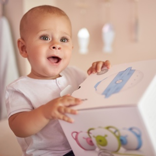A fascinated baby boy holding a box with the Nosiboo Pro Electric Nasal Aspirator