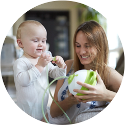 Un bébé et une mère heureux avec un mouche-bébé électrique Nosiboo Pro vert
