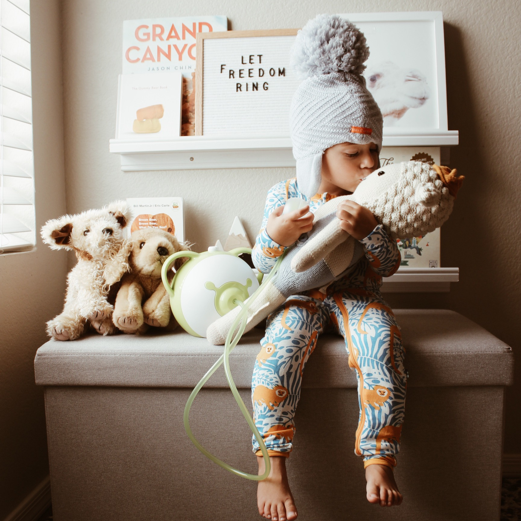 A child holding a doll next to a Nosiboo Pro electric nasal aspirator