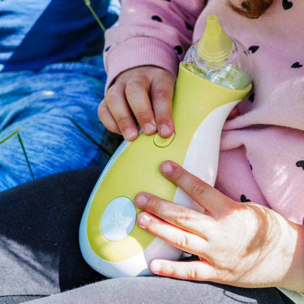 A little girl holding a Nosiboo Go portable electric nasal aspirator